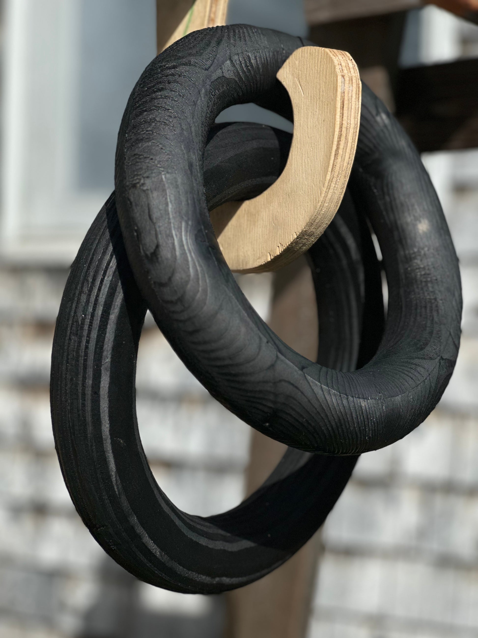 Hand-routed 3-inch thick black-dyed wooden fitness rings on a wooden linking hook for grip strength training by Rough Road Fitness.